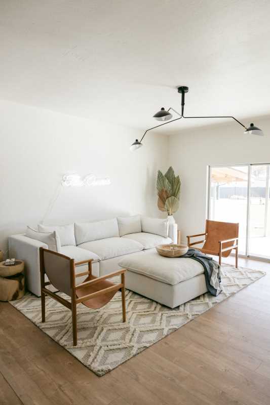 a white sofa with two wooden chairs