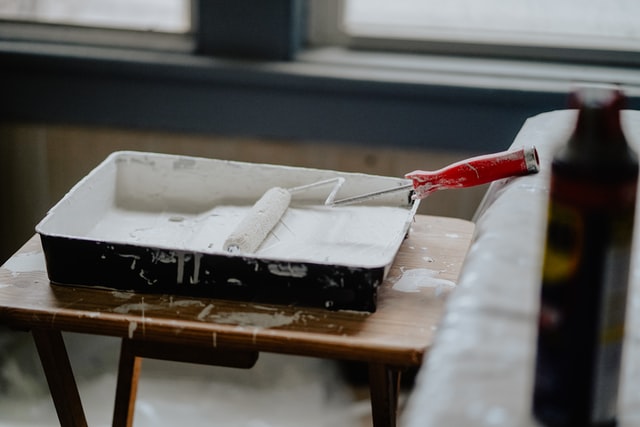 A paint roller dipped into white paint