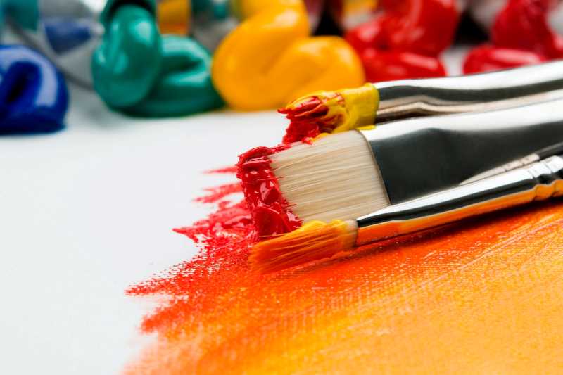 three silver paintbrushes with orange paint